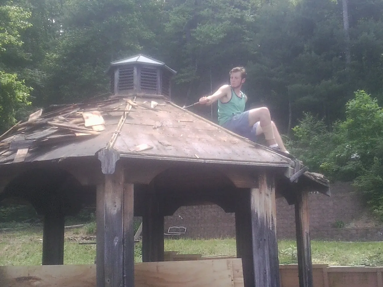 Tearing the old roof off a wooden gazebo before new shakes in Friendship
