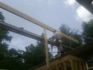 Carpenter setting a ridge beam over a new addition frame — Ice Dam Removal by Roofing Brothers in Friendship