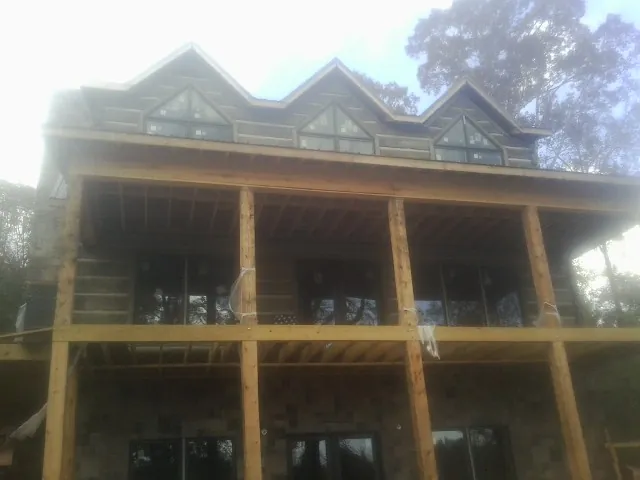 Dormers and porch framing on a large log home under construction — Roof Coating work by our crew in Friendship