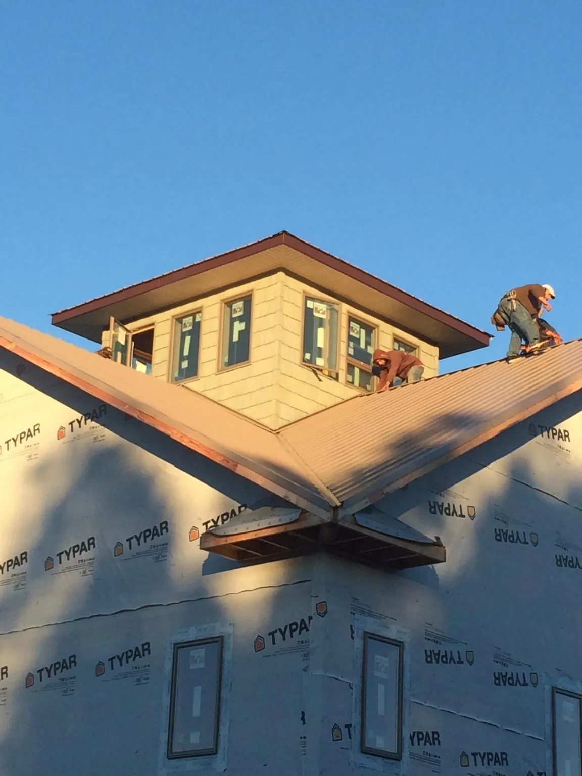 Roofers working around a rooftop cupola on a new metal roof at sunset — Roof Waterproofing in Friendship by Roofing Brothers